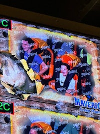 a large screen showing a group of people riding a roller coaster