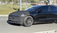 a black tesla model 3 is parked on the side of the road