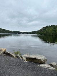 a lake surrounded by rocks and trees on a cloudy day